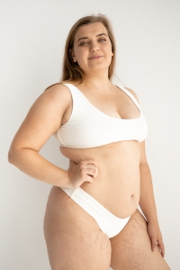 bodya biała góra stroju kąpielowego na modelce – szerokie ramiączka, sportowy fason, głęboki dekolt, widok z przodu
