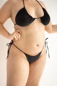 bodya czarny dół stroju kąpielowego na modelce - stringi, wycięte, wiązane, widok z przodu