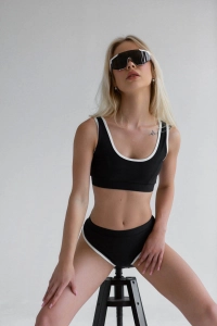 bodya czarna góra stroju kąpielowego na modelce – szerokie ramiączka, sportowy fason, z lamówką, widok z przodu